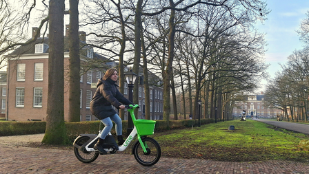 Persoon op elektrische deelfiets van Lime voor Slot Zeist.